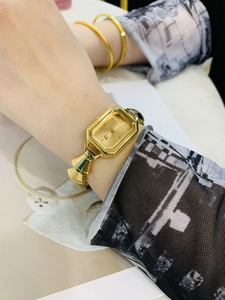 Primo piano dell'orologio al quarzo dorato con quadrante quadrato e cinturino a bracciale al polso