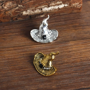 Detailed view of silver and gold witch hat brooches with rhinestones on dark wood