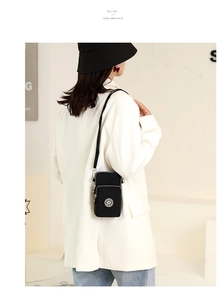Adjustable black nylon phone bag shown from a side view on a model in a white blazer
