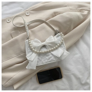 Detail of white fabric bag with silk bow decoration and elegant pearl handle strap
