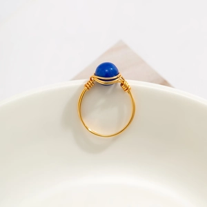 Macro shot of handmade gold wire-wrapped ring featuring a round blue stone detail