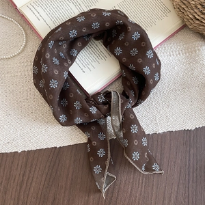 Detail of vintage brown floral silk scarf with daisy pattern on English book background