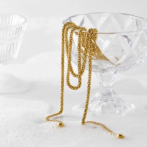 Long collier à billes dorées en acier inoxydable suspendu à un verre en cristal