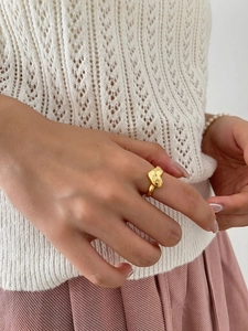 Detail of golden textured heart ring in S925 silver worn by a model in soft lighting