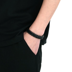 Detail of hand-woven black leather bracelet for men on wrist with a minimalist style