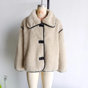 Detail of cream faux fur jacket with black leather piping and large round buttons
