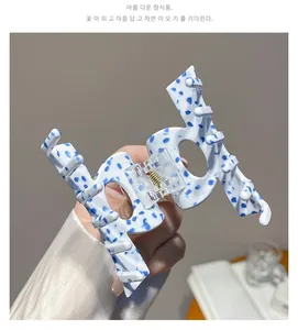 Close-up of acetic acid hair claw clip with blue marble pattern and gold metal spring
