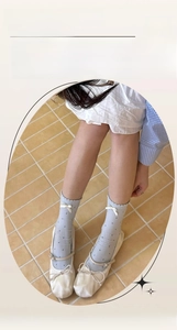 Detail of light blue crew socks featuring dark polka dots and delicate white ribbon bows
