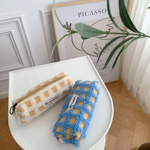 Detail view of waffle texture lamb wool pencil pouches with check pattern and zipper