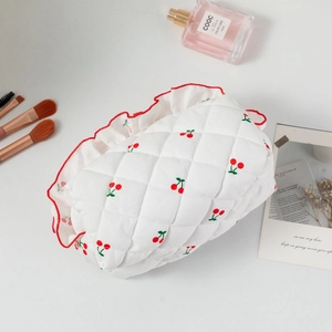 Détail de la trousse de maquillage matelassée à cerises avec bords à volants rouges