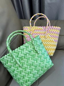 Detail of colorful hand-woven tote bags with dense plastic weave pattern on a leather sofa