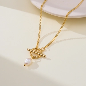 Detail of golden stainless steel necklace featuring a white pearl and T-bar OT toggle clasp