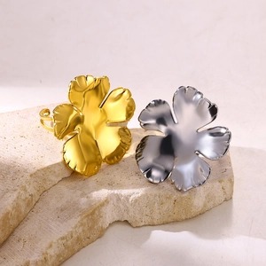 Detail view of blooming flower rings in gold and silver finish on a stone surface