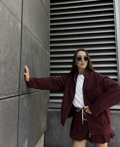 Detail shot of a burgundy zip-up jacket and matching drawstring shorts in a street style