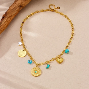 Gold stainless steel necklace with Hamsa hand, evil eye and star heart pendants on sand