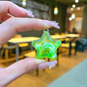 Close-up of a green star-shaped resin pendant with gold glitter and snowflake sequins