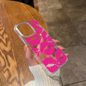 Close-up of clear phone case with pink lip pattern print held in hand over wooden desk