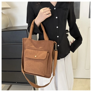 Brown corduroy tote bag detail showing front flap pocket and adjustable strap texture