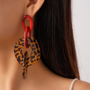 Primo piano di orecchini in acrilico leopardato con maglie rosse su una modella donna
