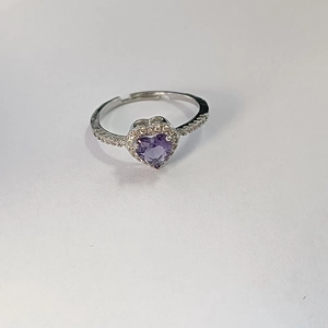 Detail shot of a silver heart ring featuring a purple zircon stone and pavé setting