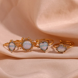 Detail of four 18K gold plated opal rings with sun and heart shapes on silk cloth