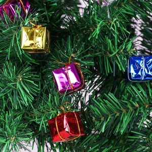 Colorful laser mini gift boxes hanging on a green Christmas tree for holiday decoration
