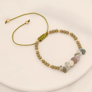 Handmade woven bracelet with natural green stones and matte beads on white tray