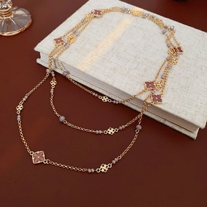 Detail of layered gold necklace with pink flower charms and gray beads on a book