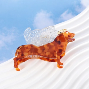 Cute dachshund hair claw with tortoise shell pattern and glittery wings on blue sky backdrop