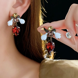 Detailed close-up of a vintage bee-style earring with a red pear-shaped gemstone drop