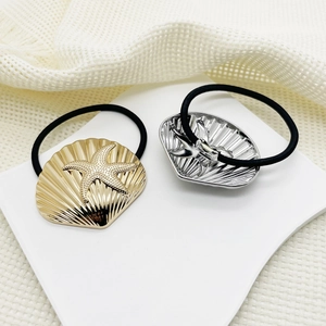 Detail of alloy hair ties with gold and silver starfish shell charms on white card