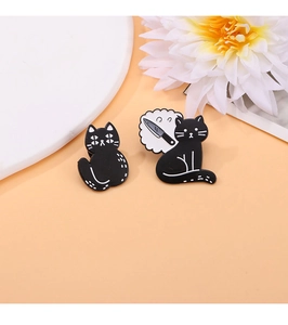 Détail de badges en émail chat noir avec points blancs et bulle de poignard sur fond orange