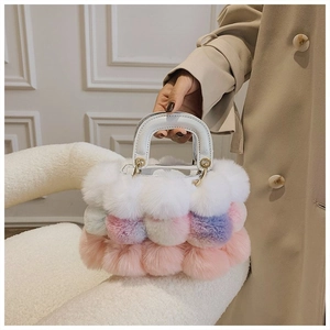 Detail of plush faux fur pom-pom handbag with white crocodile pattern handle