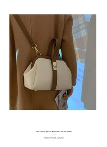 Detail shot of vintage contrast color doctor bag with gold clasp on brown coat