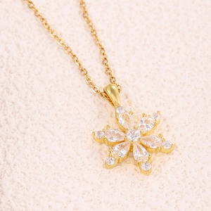 Elegant gold snowflake pendant necklace with sparkling cubic zirconia on textured background