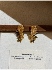 Detail of vintage gold lava metal earrings with tiger eye stone beads on velvet display