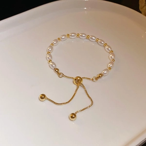 Détail d'un bracelet en perles d'eau douce vintage avec fermoir réglable doré sur céramique