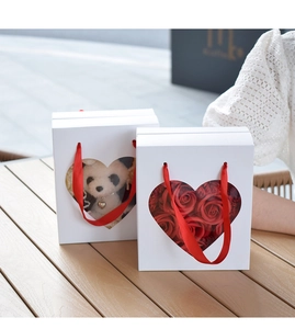 Close-up of white gift boxes with heart windows, plush panda, and red soap flowers