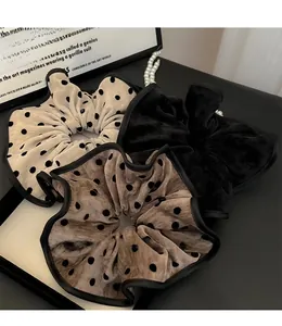 Detailed view of three oversized velvet hair scrunchies with elegant polka dot patterns