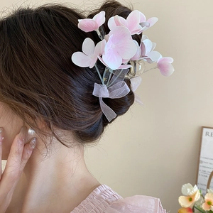 Detailed view of the pink and white fabric flower hair claw with a sheer organza bow