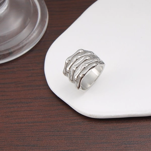 Detailed view of silver skeleton hand bone ring on a white ceramic plate backdrop