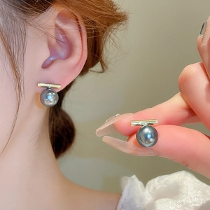 Détail de boucles d'oreilles perle grise avec barre dorée et finition brillante chic