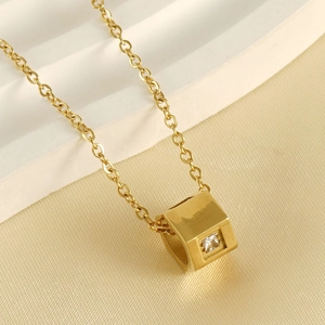 Close-up of a gold 18k plated cubic pendant necklace with a square zircon on silk fabric