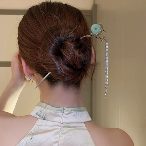 Detailed view of silver butterfly hairpin with green stone and sparkling tassels