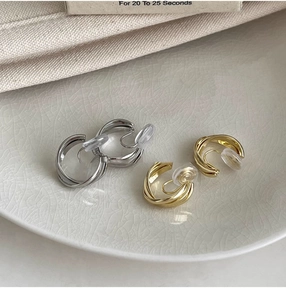 Détail de boucles d'oreilles clips en C torsadées or et argent avec coussinets confort