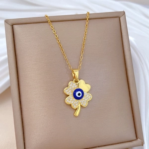 Macro view of gold clover pendant with blue evil eye and sparkling cubic zirconia stones