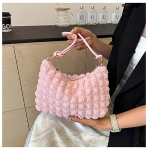 Close-up of pink bubble texture shoulder bag held by a model in a cozy cafe setting