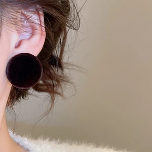 Close-up of a model wearing minimalist dark brown flocked round button stud earrings