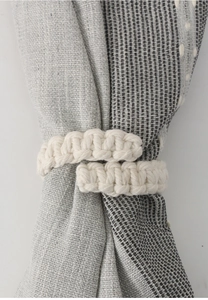 Detail shot of handcrafted beige macrame curtain tieback with woven cotton rope texture