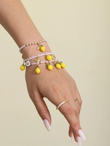 Detail of beaded lemon bracelet with golden bee and white daisy charms on a wrist